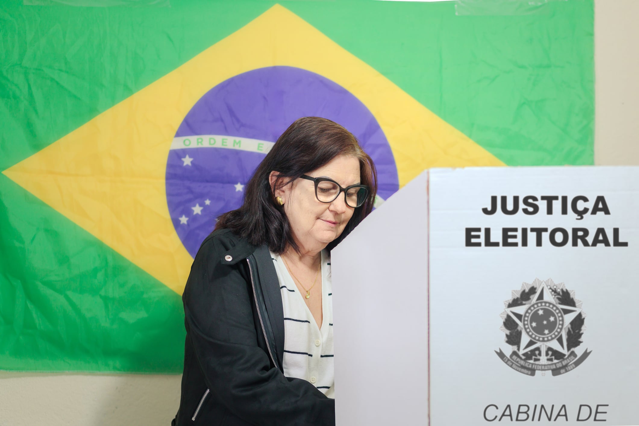 A woman at the ballot box in front of the Brazilian falg